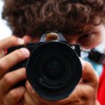 man in red shirt holding black camera