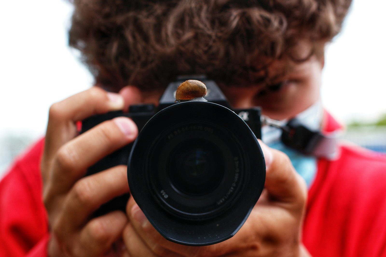 man in red shirt holding black camera