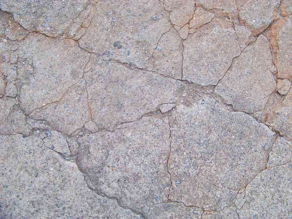 Béton fissuré aux tons grisâtres, craquelé, sans éléments extérieurs