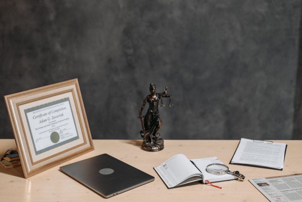 Un bureau avec diplôme statue de justice ordinateur cahier et documents