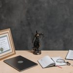Un bureau avec diplôme statue de justice ordinateur cahier et documents