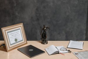 Un bureau avec diplôme statue de justice ordinateur cahier et documents