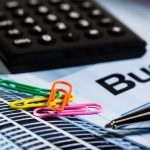 Calculatrice, papier, stylo et trombones colorés sur document d'entreprise