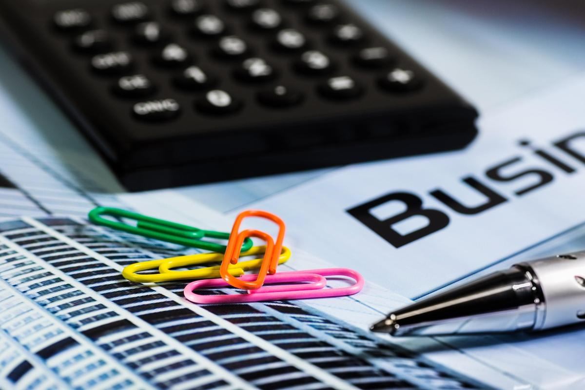 Calculatrice, papier, stylo et trombones colorés sur document d'entreprise